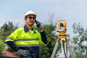 landmeter civiel ingenieur gebruik makend van de telefoon met uitrusting theodoliet of totaal positionering station Aan de bouw plaats. foto