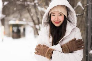 mooie jonge aziatische vrouw die lacht gelukkig voor reizen in sneeuw winterseizoen foto