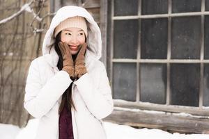 mooie jonge aziatische vrouw die lacht gelukkig voor reizen in sneeuw winterseizoen foto