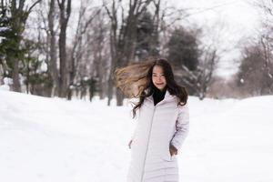 mooie jonge aziatische vrouw die lacht gelukkig voor reizen in sneeuw winterseizoen foto