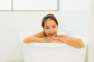 portret mooie jonge aziatische vrouw neemt een badkuip in de badkamer foto