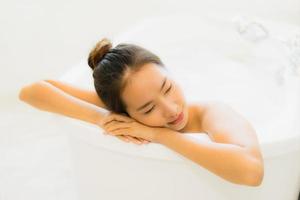 portret mooie jonge aziatische vrouw neemt een badkuip in de badkamer foto