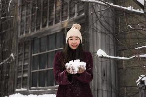 mooie jonge aziatische vrouw die lacht gelukkig voor reizen in sneeuw winterseizoen foto