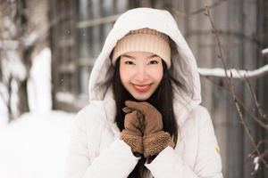 mooie jonge aziatische vrouw die lacht gelukkig voor reizen in sneeuw winterseizoen foto