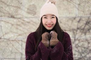 mooie jonge aziatische vrouw die lacht gelukkig voor reizen in sneeuw winterseizoen foto