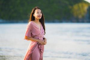 portret jonge mooie Aziatische vrouw lopen glimlach en gelukkig op het strand zee en oceaan and foto