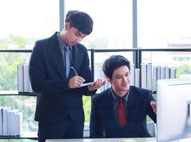 twee jonge zakenlieden zitten en werken op laptops in een modern kantoor, het zijn jonge, actieve zakenlieden foto