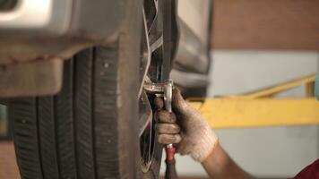 Aziatisch Mens auto monteur vervangen een auto band in garage werkplaats. . auto onderhoud, auto zorg centrum verwijdert de wiel, reparatie en onderhoud van de auto in onderhoud. foto