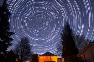 ster trails over- een klein cabine in de nacht lucht generatief ai foto