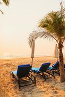 parasol strandstoel met palmboom en zee strand bij zonsopgang - vakantie en vakantie concept foto