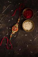raksha bandhan achtergrond met een elegante rakhi, rijstkorrels en kumkum. een traditionele Indiase polsband die een symbool is van liefde tussen broers en zussen. foto