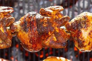 geroosterde kippen aan het spit gegrild boven vuur van een grote barbecue foto