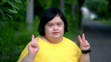 Aziatisch jong vrouw naar beneden syndroom twee duim omhoog glimlach terwijl oefenen in de park. foto