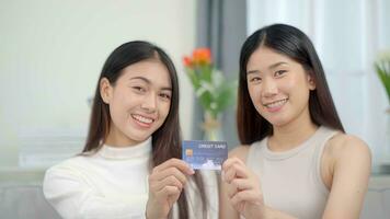 twee Aziatisch glimlachen Dames in tonen credit kaart. online succes kopen uitverkoop. foto