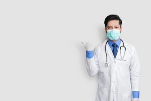 dokter dragen masker uniform glimlachen tijdens het presenteren en wijzen geïsoleerd op een witte achtergrond met kopie ruimte