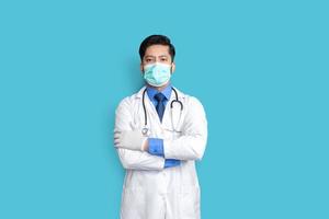 jonge mannelijke dokter gezicht bedekt met masker en arm kruis over geïsoleerde achtergrond