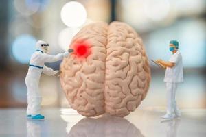 miniatuur mensen dokter en verpleegster observeren en discussiëren over het menselijk brein