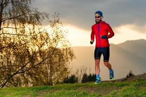 atleet rent in de bergen bij zonsondergang foto