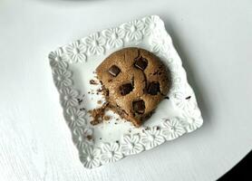 chocola spaander koekje Aan een wit bord met een gouden lepel Aan wit houten tafel, top visie foto