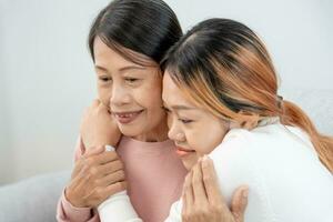 moeder dag, schattig Aziatisch tiener meisje knuffelen volwassen midden- leeftijd mamma. liefde, kus, zorg, gelukkig glimlach genieten familie tijd. vieren speciaal gelegenheid, gelukkig verjaardag, vrolijk kerstmis. speciaal dag foto