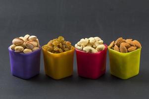 gezonde mix droog fruit en noten op donkere achtergrond. amandelen, pistache, cashewnoten, rozijnen foto