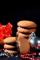 koekjes - stapel heerlijke roomkoekjes gevuld met chocoladeroom versierd met kerstversieringen op zwarte achtergrond
