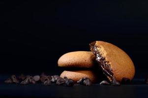 koekjes gevuld met chocoladeroom. chocolade crème koekjes. bruine chocoladekoekjes met roomvulling op zwarte achtergrond. foto