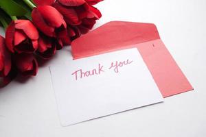 bedankt bericht, envelop en rode tulp bloem op witte achtergrond