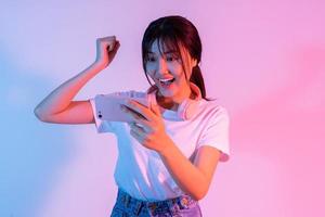 jong Aziatisch meisje speelspel op telefoon met opwinding foto