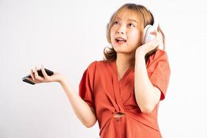 jong Aziatisch meisje dat haar telefoon gebruikt en een koptelefoon draagt om van muziek te genieten foto