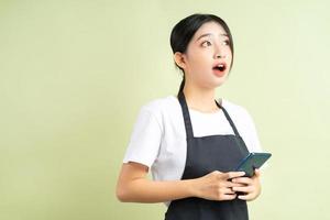 Aziatische serveerster die de telefoon vasthoudt met een verbaasd gezicht foto