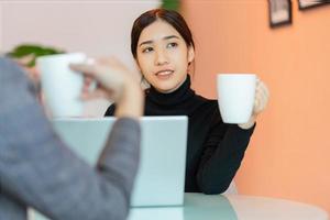Aziatische vrouw zitten en chatten met collega's in de coffeeshop na het werk