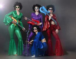 meisjes in helder glimmend kostuums en pruiken met gitaren. wijnoogst muziek- disco band voor Dames in disco stijl. foto