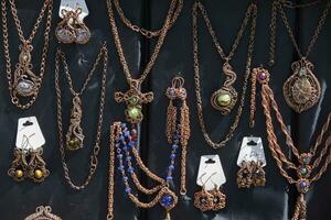 hangers en broches met goedkoop stenen hangen Aan kettingen. uitverkoop van handgemaakt sieraden Bij de eerlijk. foto