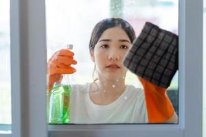 mooie aziatische vrouw die de glazen deur van de slaapkamer schoonmaakt foto