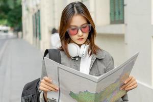 Aziatische vrouwelijke toerist leest de kaart om haar weg te vinden foto