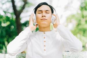 knappe aziatische man die van muziek geniet in het park foto