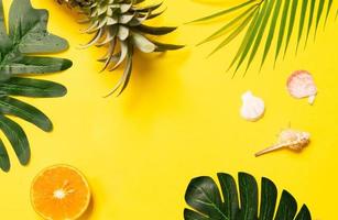 zomerconcept met zeeschelp, sinaasappel en blad op gele achtergrond foto