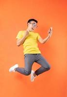 Aziatische man in geel t-shirt springen op oranje achtergrond foto
