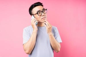 portret van aziatische man met smartphone op roze achtergrond foto