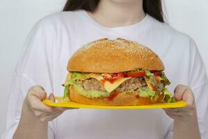 handen houden een dienblad met een groot hamburger. foto