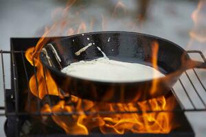 pannekoeken zijn gekookt Aan een brand Bij de maslenitsa vakantie. foto