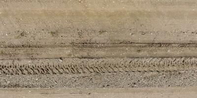 panorama van weg van bovenstaand Aan oppervlakte van grind weg met auto band sporen in platteland foto