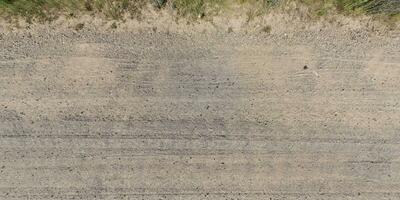 panorama van weg van bovenstaand Aan oppervlakte van grind weg met auto band sporen in platteland foto