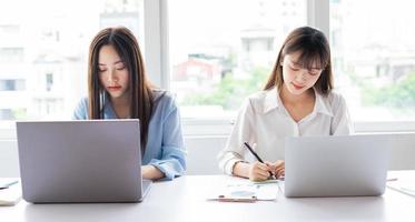 twee jonge aziatische vrouwen zijn gefocust op werken