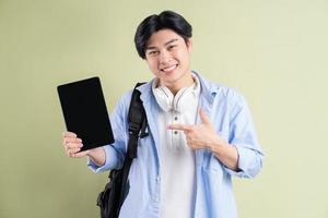 mannelijke Aziatische student wijst zijn vinger naar de tablet met een leeg scherm blank