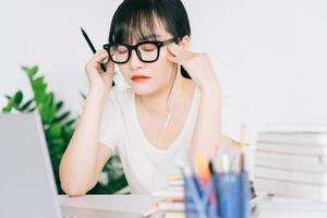 Aziatische zakenvrouw is moe en hoofdpijn met veel werk aan de deadline foto