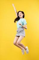 jong Aziatisch meisje dat op gele achtergrond springt foto