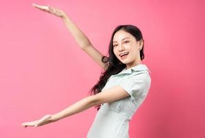 jonge aziatische vrouw die zich voordeed op roze achtergrond