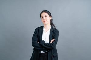 gelukkige aziatische vrouw met blij gezicht in kantoorkleren op grijze achtergrond foto